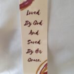 Love and Grace Laminated Bookmark classic tan background with red, tan, and white multicolored border frames the quote God’s love and grace in a classic red serif font by Beatrice Garrett.